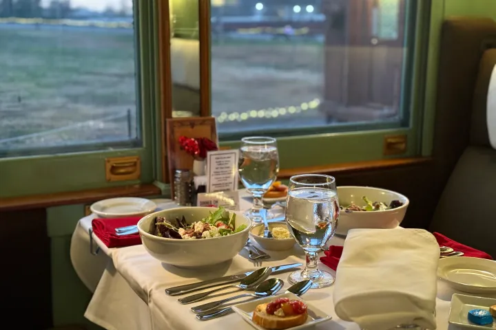 Dinner table with wine glasses, bread, and salads set aboard the Tennessee Valley Railroad’s Valentine Train Ride.