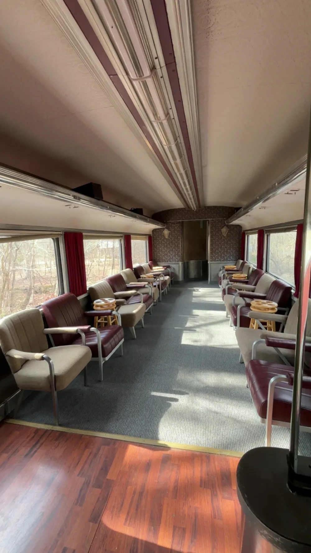 Interior of an empty vintage train car with rows of seats and windows on both sides.