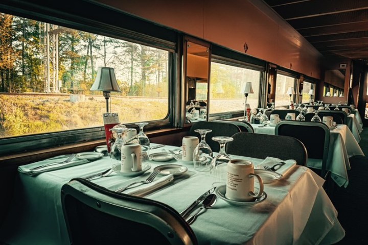 Vintage train dining car breakfast setup with white tablecloths and scenic window views
