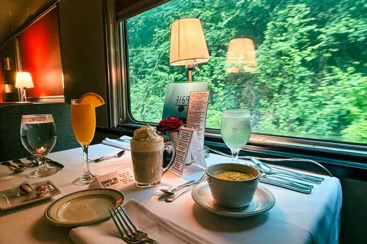 Dinner Train table setting featuring soup, artisan bread, beverages, and dessert served onboard a vintage dining car