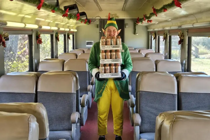 Elf standing in a decorated railcar aboard Santa’s Hiwassee Train Ride