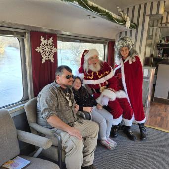 Family seated with Santa and Mrs. Claus aboard Santa’s Hiwassee Train Ride