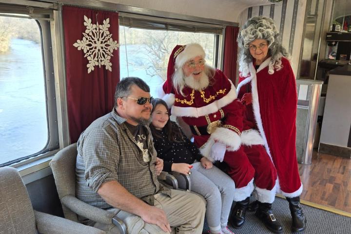 Family seated with Santa and Mrs. Claus aboard Santa’s Hiwassee Train Ride