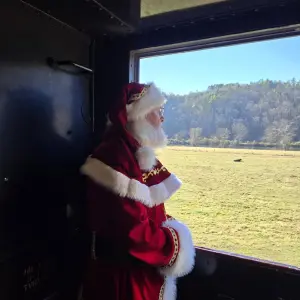 Santa Claus waving from a train window aboard Santa’s Hiwassee Train Ride