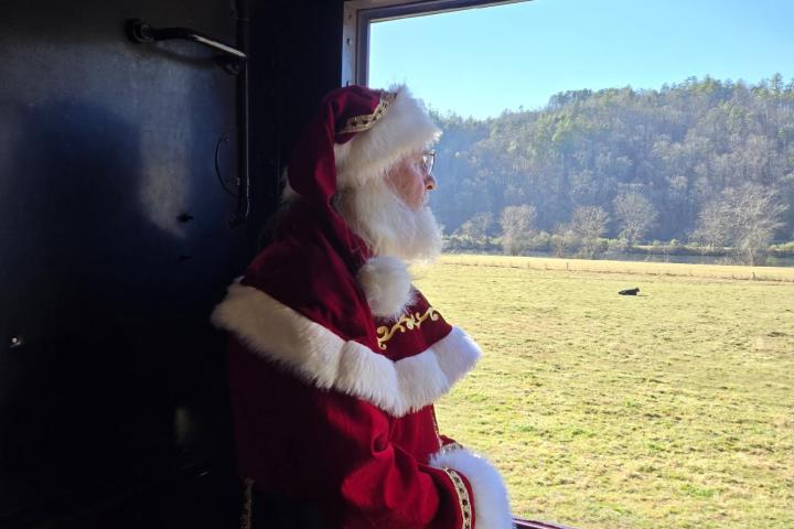 Santa Claus waving from a train window aboard Santa’s Hiwassee Train Ride