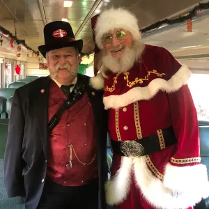 Santa Claus greeting passengers aboard the Santa’s Hiwassee Holiday Train with a uniformed conductor