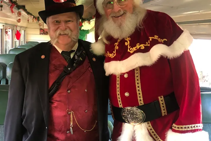 Santa Claus greeting passengers aboard the Santa’s Hiwassee Holiday Train with a uniformed conductor