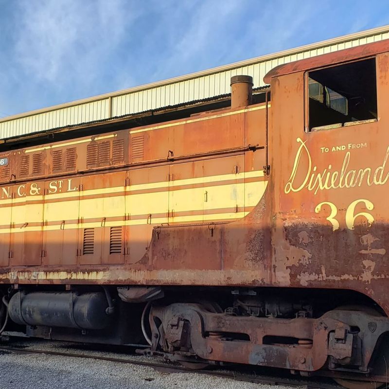 a train on a track with graffiti on the side of a building