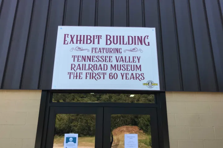 This sign is located at the entrance of the Tennessee Valley Railroad Museum's Exhibit Building. It welcomes visitors to the museum and tells them what they can expect to see inside.