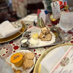 Tea table with scones, cream, and holiday decor on a lace tablecloth.