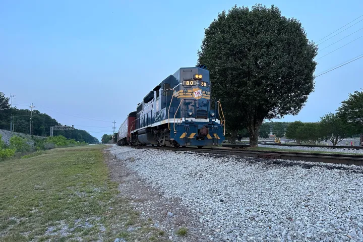 a large long train on a train track with trees in the background