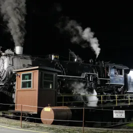 a steam engine on a train track with smoke coming out of it