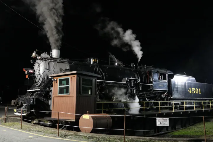 a steam engine on a train track with smoke coming out of it