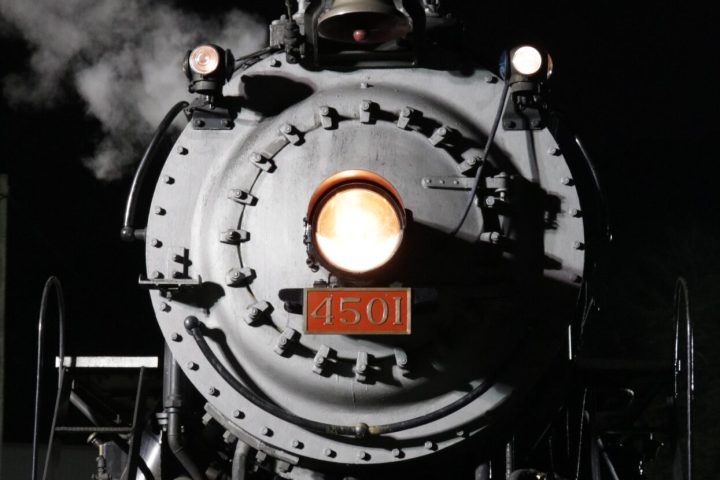 a steam engine on a train track with smoke coming out of it