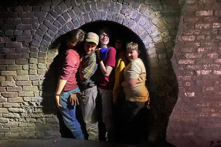a group of people standing next to a brick wall