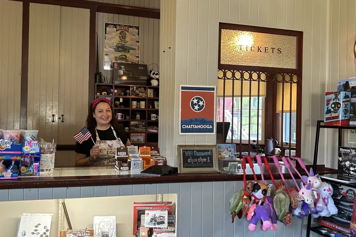 Gift shop interior with toys, souvenirs, and a counter with a staff member holding a small flag.