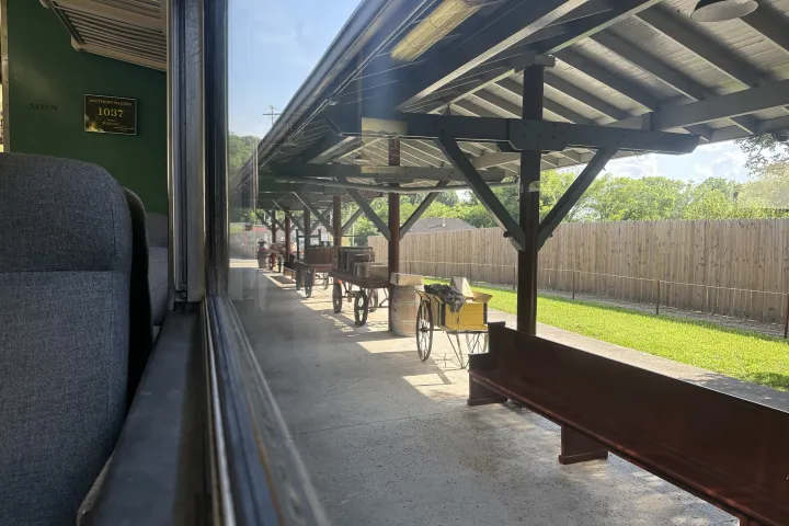 View of train tracks and platform with vintage luggage carts from a window.
