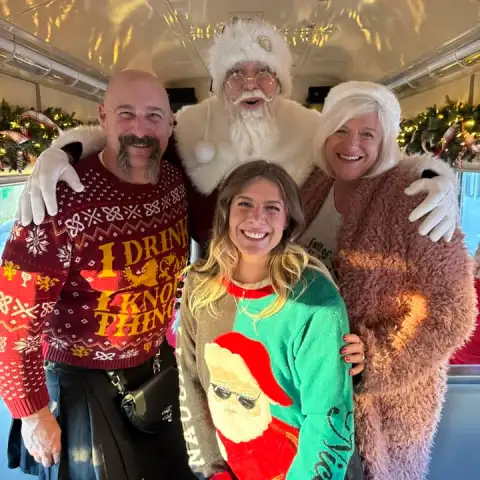 Family posing with Santa inside a festively decorated holiday train car at the Tennessee Valley Railroad Museum