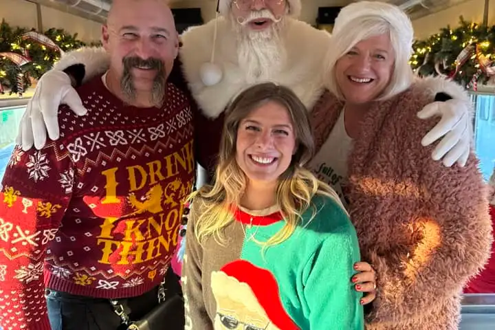 Family posing with Santa inside a festively decorated holiday train car at the Tennessee Valley Railroad Museum