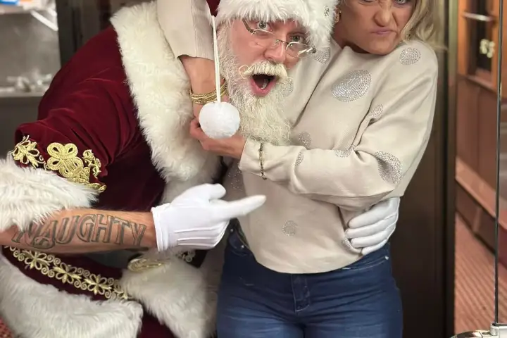 Santa playfully poses with a woman making a funny face on a train.