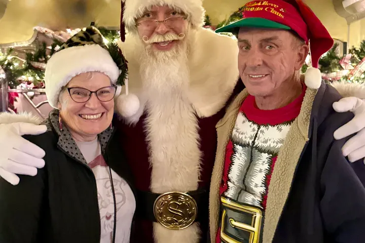 Santa smiling with two guests during the Nightcap With St. Nick 21+ Christmas train ride at the Tennessee Valley Railroad Museum.