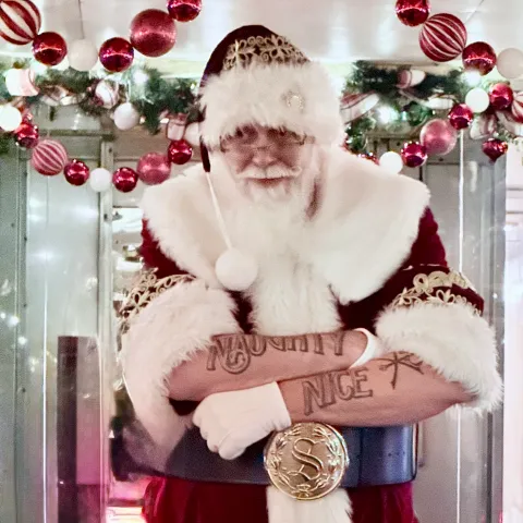 Santa Claus with festive tattoos posing inside the decorated Nightcap with St. Nick holiday train car at Tennessee Valley Railroad Museum.