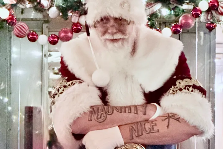 Santa Claus with festive tattoos posing inside the decorated Nightcap with St. Nick holiday train car at Tennessee Valley Railroad Museum.