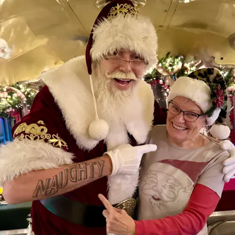 Santa with festive tattoos posing with guest during Nightcap With St. Nick at Tennessee Valley Railroad Museum.