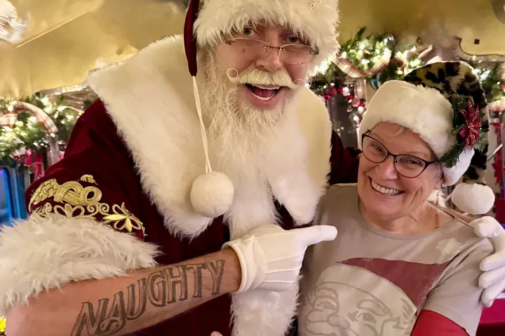 Santa with festive tattoos posing with guest during Nightcap With St. Nick at Tennessee Valley Railroad Museum.