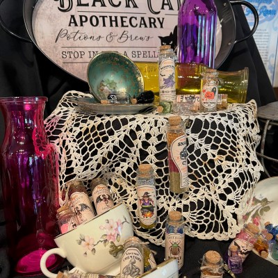 Antique apothecary display with potion bottles, teacups, and decorative glassware.