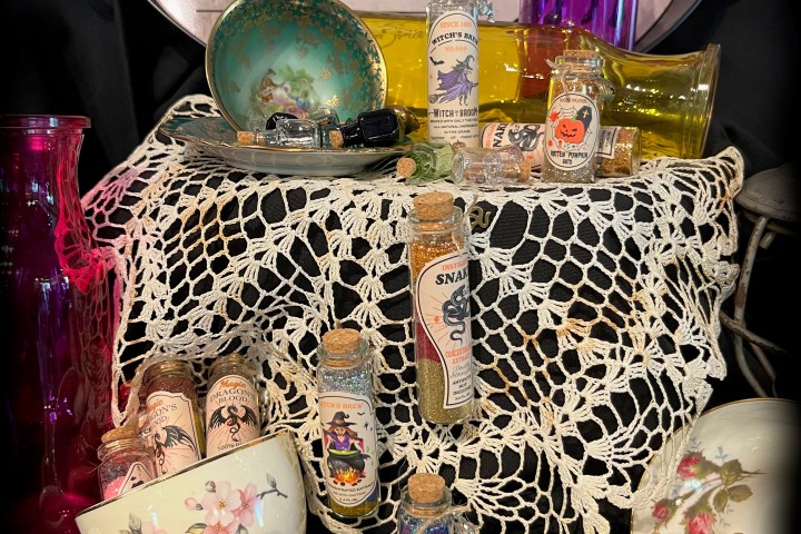 Apothecary setup with potions, bottles, lace cloth, teacups, and a Black Cat sign.