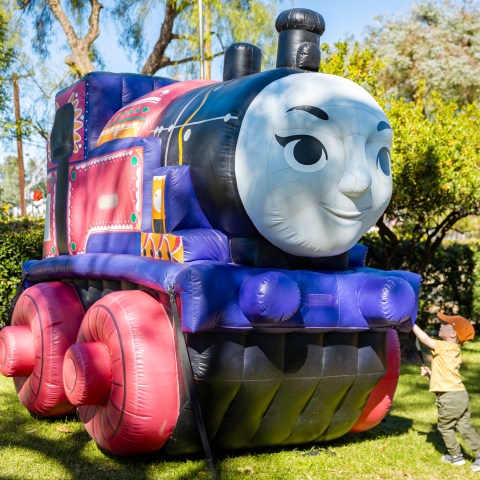 Inflatable Thomas the Train with children playing nearby on a sunny day at the event.