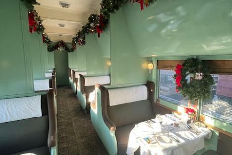 Vintage train dining car decorated for Christmas with garlands and wreaths.