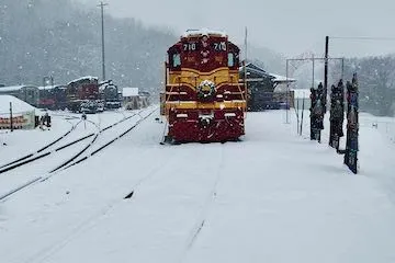 Red and yellow train on snowy tracks in a winter landscape.