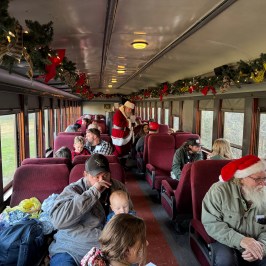 “Santa walking down the decorated Summerville Christmas train aisle greeting families.