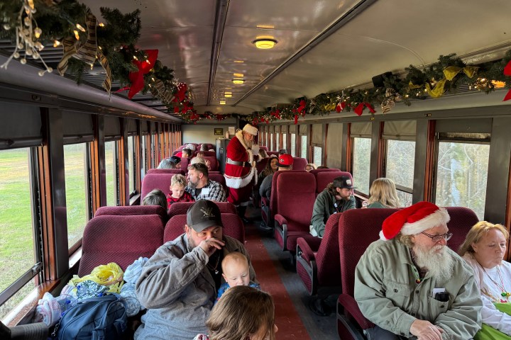 “Santa walking down the decorated Summerville Christmas train aisle greeting families.