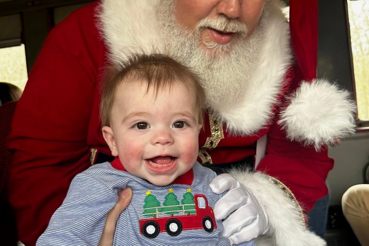 Santa holding a smiling baby aboard the Summerville Santa Special holiday train.