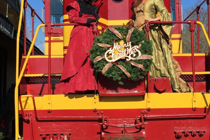 Santa’s Summerville train ready for holiday passengers with festive wreath and elf at the front.