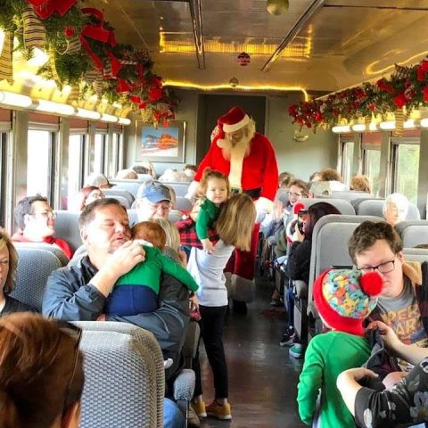 Children greet Santa aboard the Summerville Santa Special decorated with garland and lights.