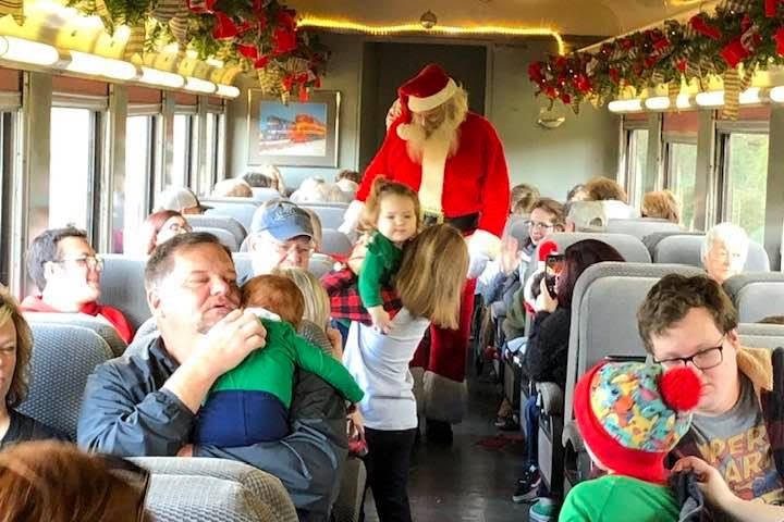 Children greet Santa aboard the Summerville Santa Special decorated with garland and lights.