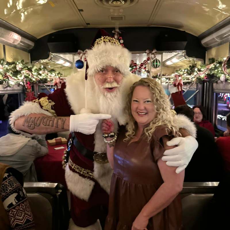 Santa Claus posing with a smiling guest inside the decorated NightCaps dining car.
