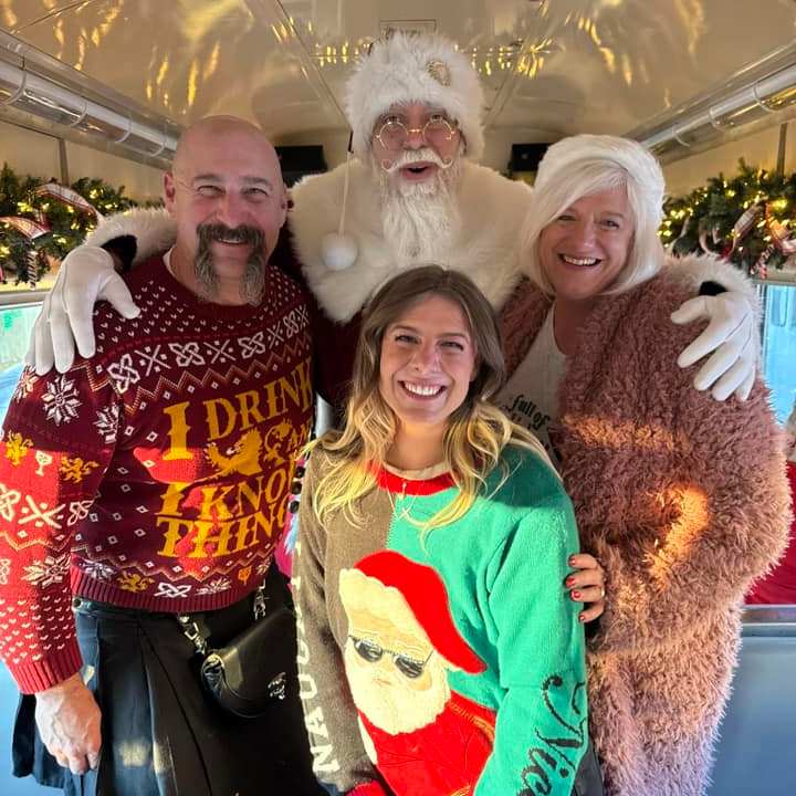 Family posing with Santa aboard the holiday-themed NightCaps train.