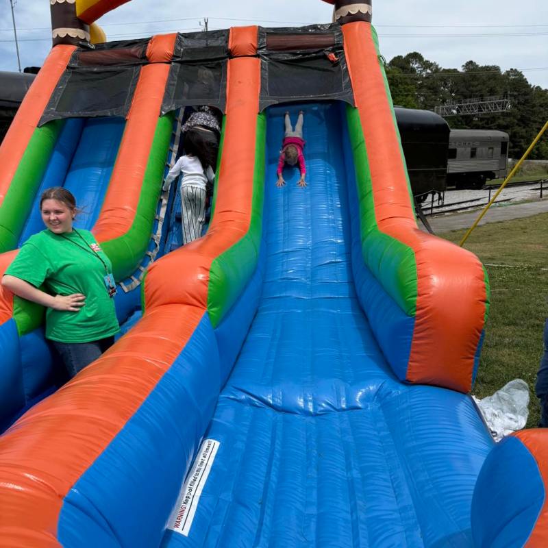 Child sliding down a colorful inflatable slide outdoors.