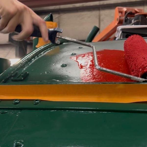 Hand painting machine green with red roller and masking tape.